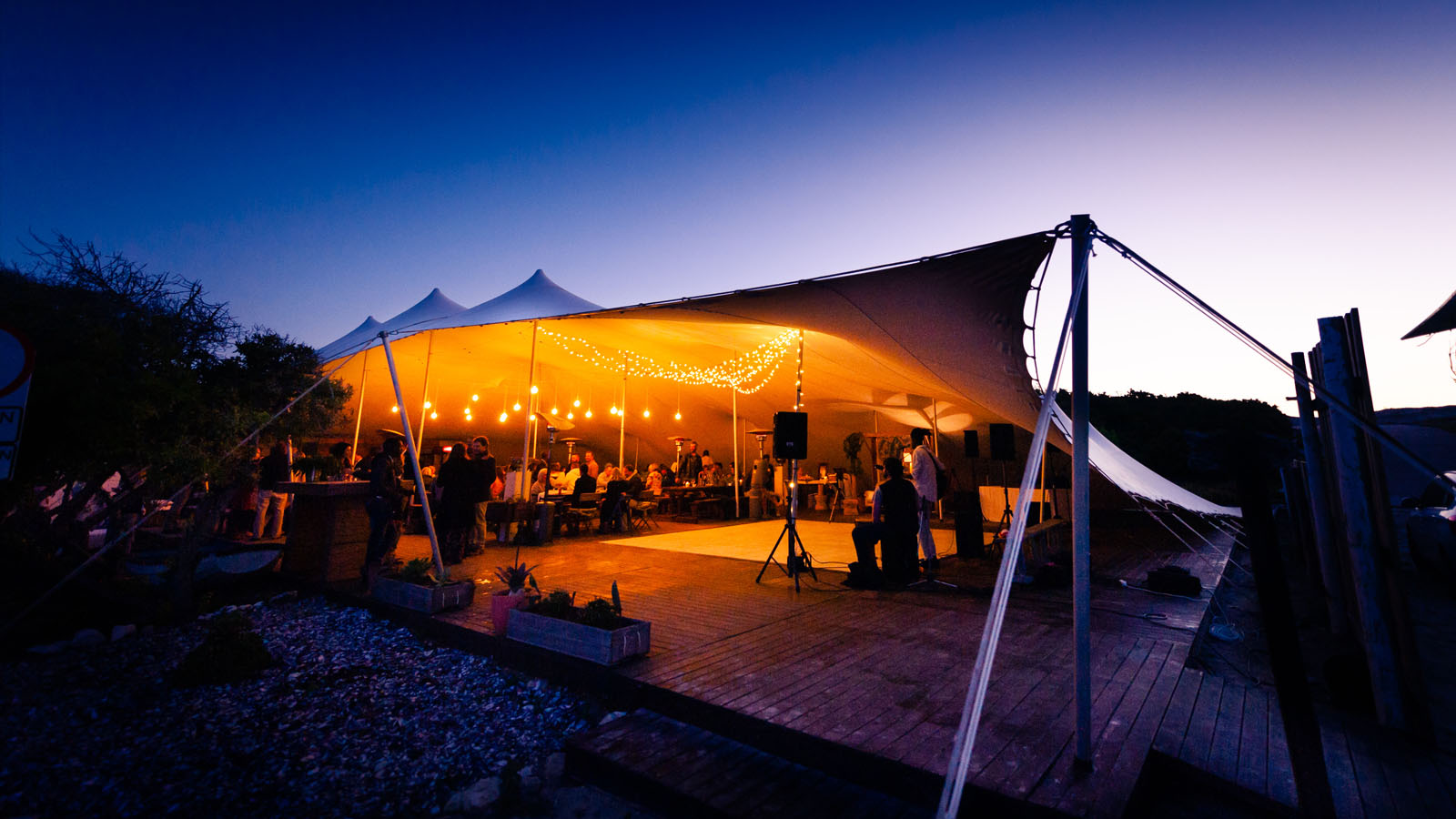 Wedding guests inside a large Bedouin tent in the early evening.